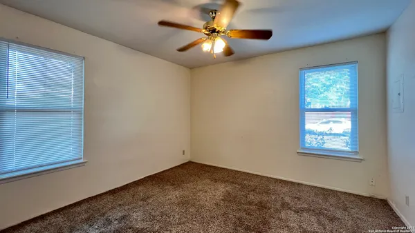 an empty room with windows and fan