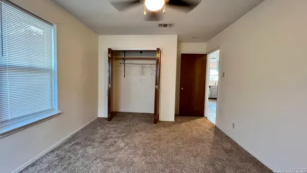 an empty room with closet and a chandelier fan