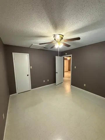 a view of an empty room with a chandelier fan