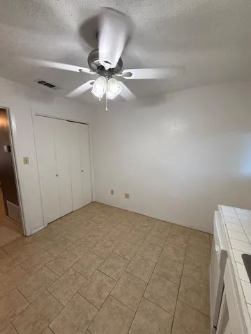 an empty room with a chandelier fan and windows