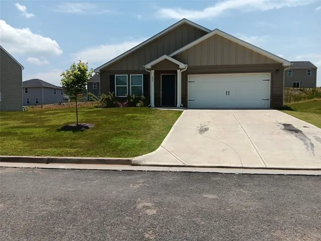 a view of a white house with a yard and a large tree
