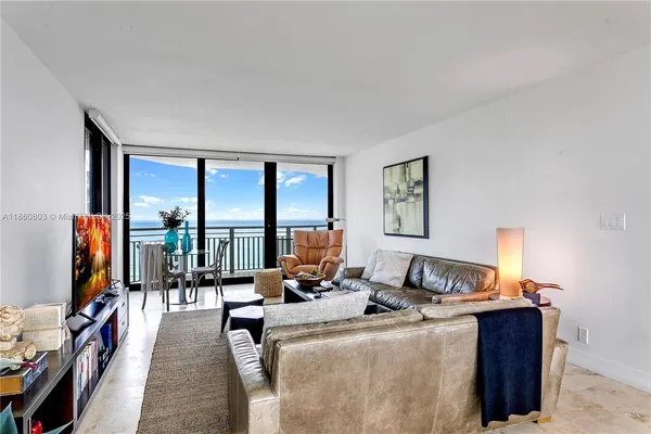 a living room with furniture a floor to ceiling window and a flat screen tv