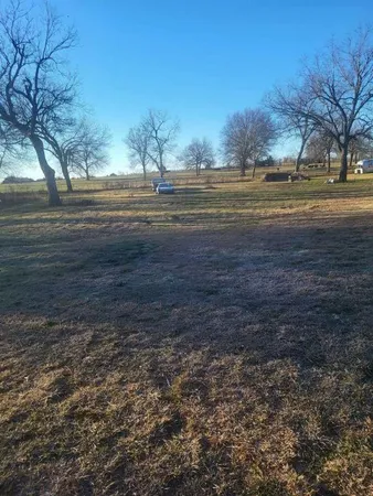 a view of dirt yard with wooden fence