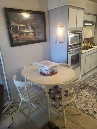 a kitchen with granite countertop a dining table chairs cabinets and stainless steel appliances