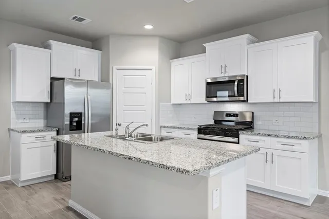 a kitchen with kitchen island granite countertop a sink stove and refrigerator