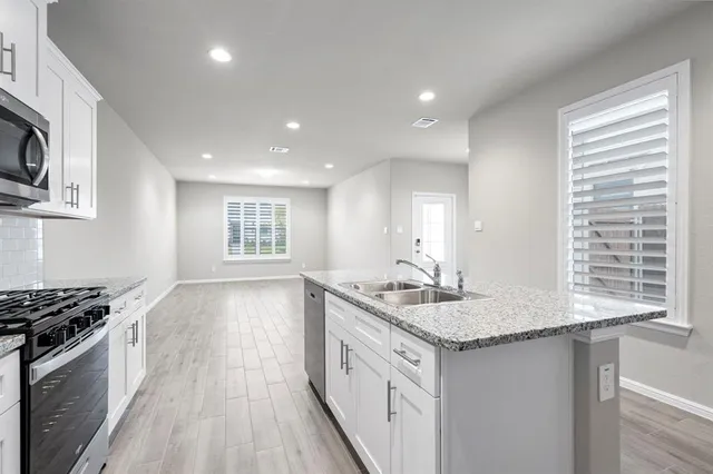 a kitchen with stainless steel appliances granite countertop a sink stove and cabinets