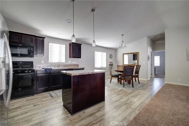 a kitchen with stainless steel appliances granite countertop a stove top oven a sink dishwasher a dining table and chairs with wooden floor