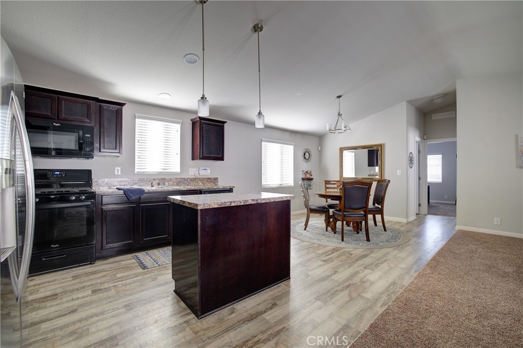 3700 Buchanan, Unit 25 Corona, CA 92503 - Photo 16 of 27 a kitchen with stainless steel appliances granite countertop a stove top oven a sink dishwasher a dining table and chairs with wooden floor