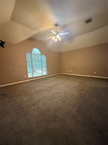 an empty room with chandelier fan and windows