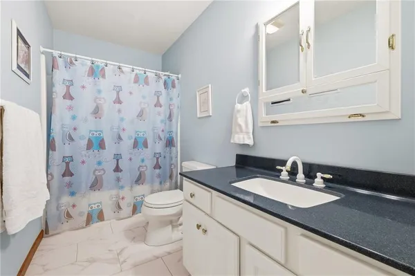 a bathroom with a granite countertop sink a toilet and a mirror