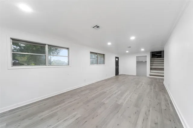 a view of empty room with wooden floor and windows