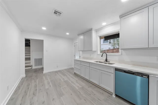 a view of a kitchen with a sink and dishwasher wooden cabinets
