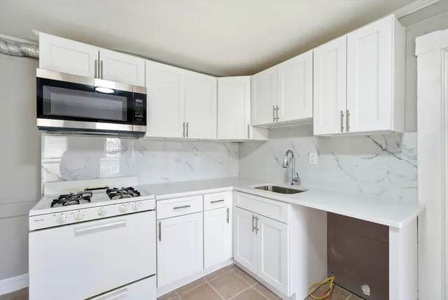 a kitchen with granite countertop white cabinets sink and stainless steel appliances