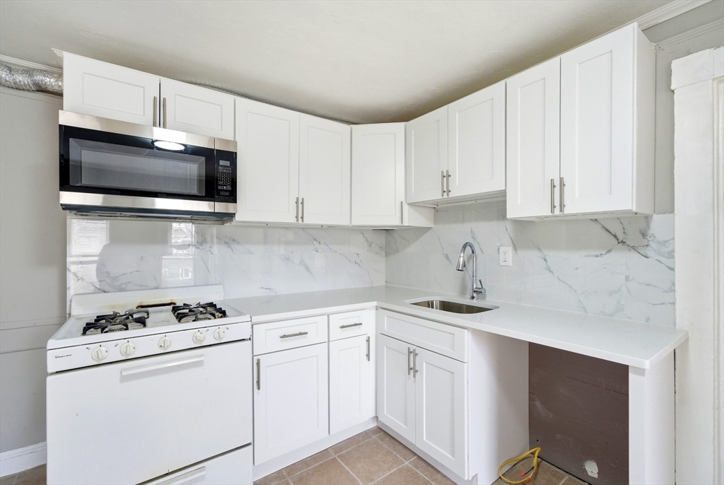 29-31 Auburn Street, Unit 2L Everett, MA 02149 - Photo 3 of 18 a kitchen with granite countertop white cabinets sink and stainless steel appliances