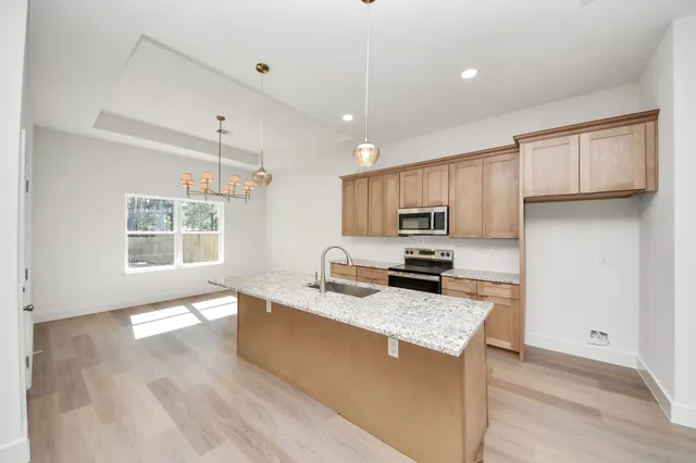 a kitchen with kitchen island granite countertop a sink a counter top space appliances and cabinets