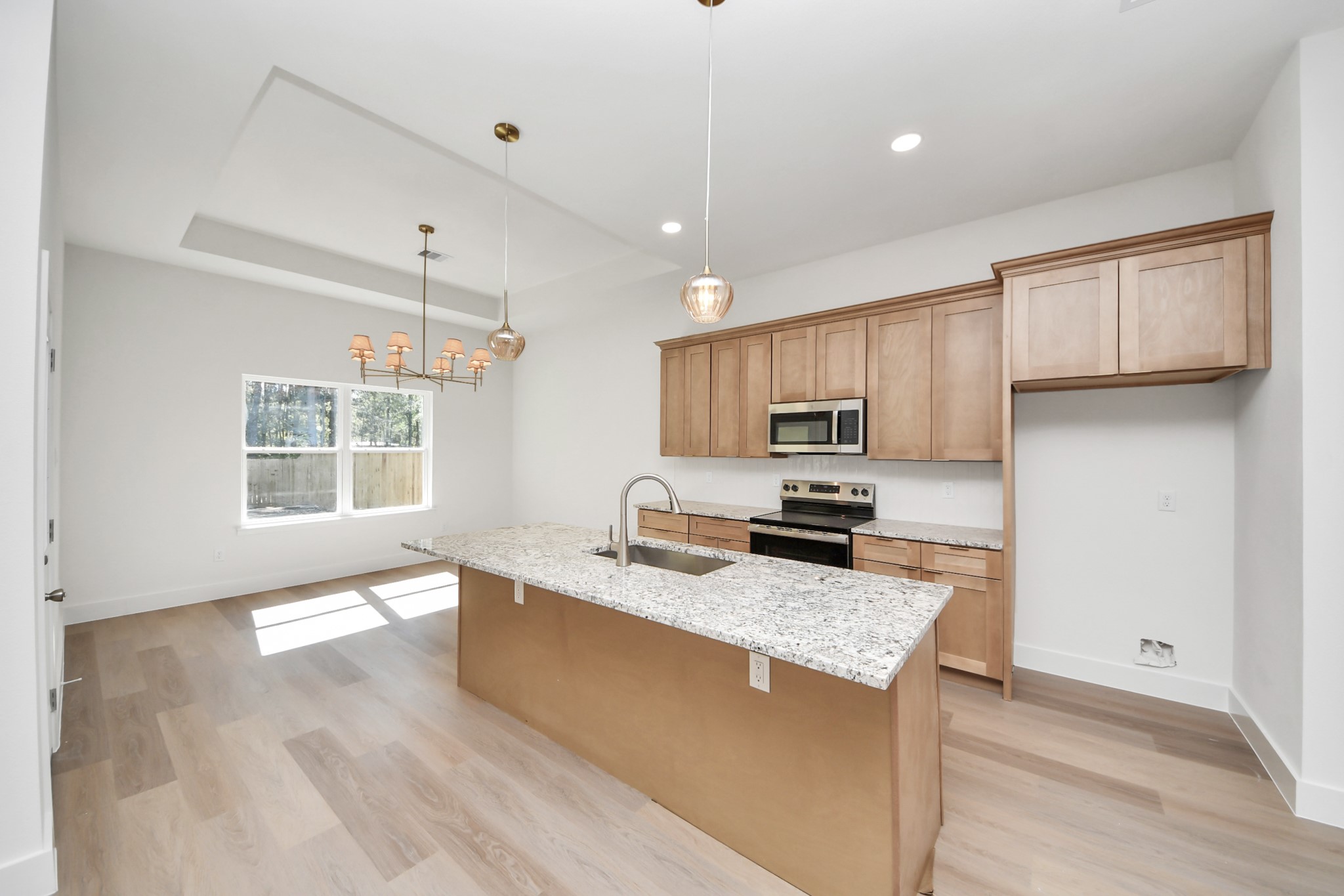 16280 Jeet Street Conroe, TX 77306 - Photo 11 of 44 a large kitchen with granite countertop a stove a sink a refrigerator and white cabinets with wooden floor