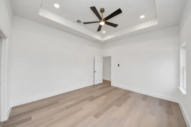 an empty room with wooden floor and ceiling fan
