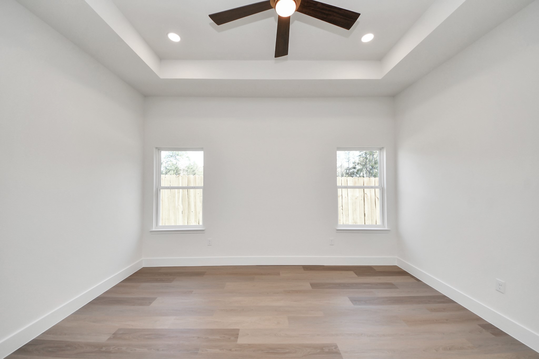 16280 Jeet Street Conroe, TX 77306 - Photo 26 of 44 an empty room with wooden floor chandelier fan and windows