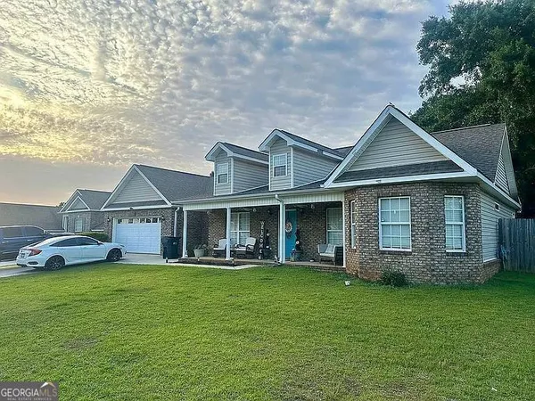 a front view of a house with a garden and trees