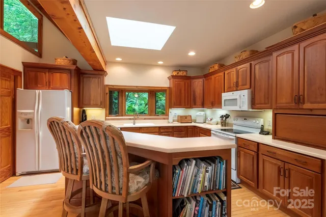 a kitchen with stainless steel appliances granite countertop a table chairs sink refrigerator and cabinets
