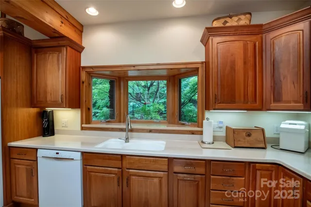 a kitchen with stainless steel appliances wooden cabinets a sink and a large window