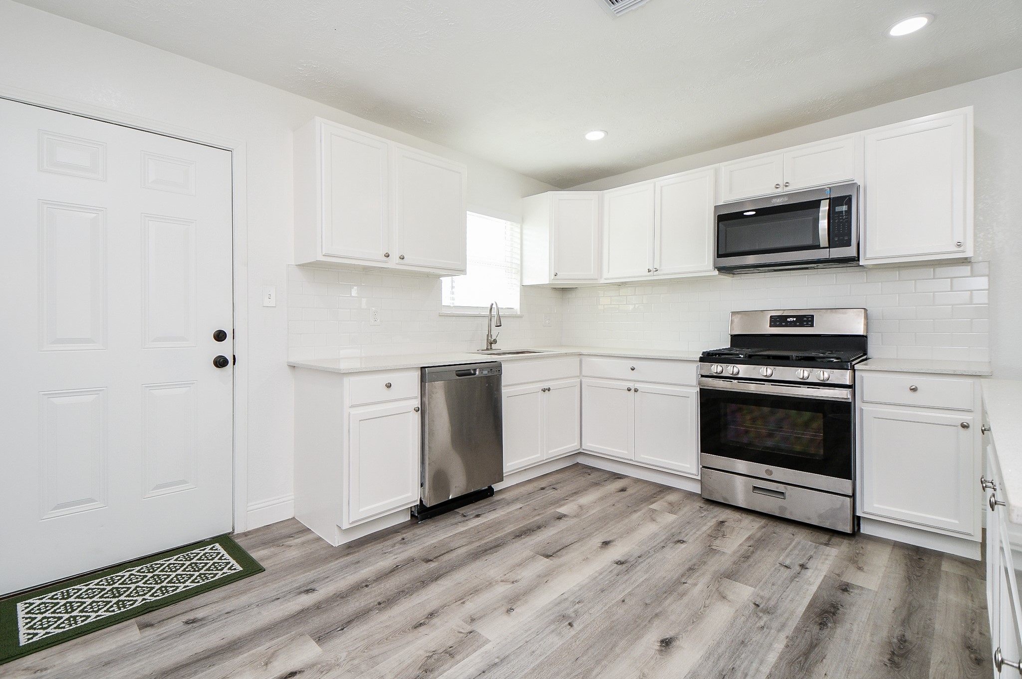 5814 Belneath Street Houston, TX 77033 - Photo 13 of 32 a kitchen with stainless steel appliances a stove a microwave and white cabinets