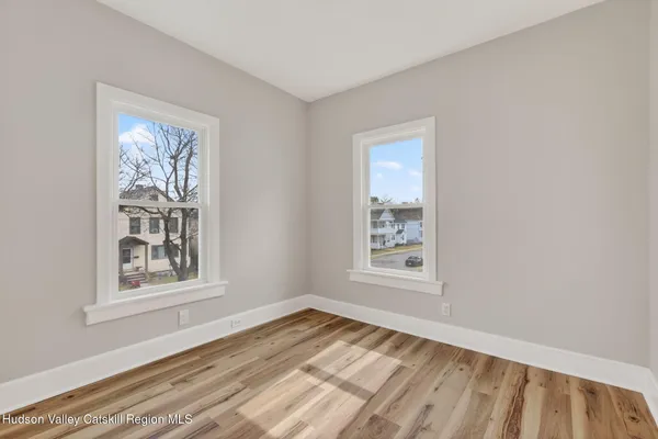 a view of an empty room with a window and wooden floor