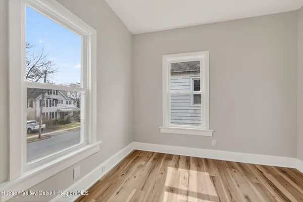 a view of an empty room with a window and wooden floor