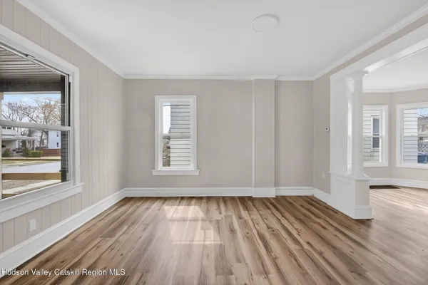 a view of an empty room with wooden floor and a window