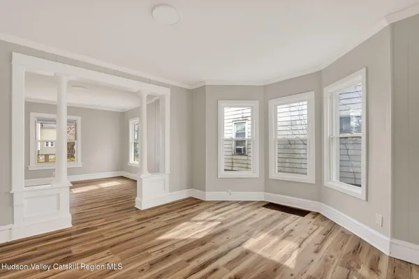a view of an empty room with wooden floor and a window