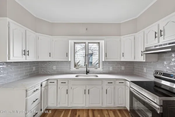 a kitchen with granite countertop a sink stainless steel appliances white cabinets and a window