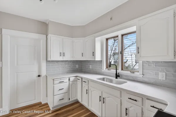 a kitchen with white cabinets and sink