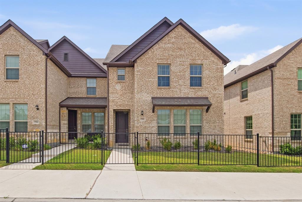 a view of a small house in front of a brick house with large windows