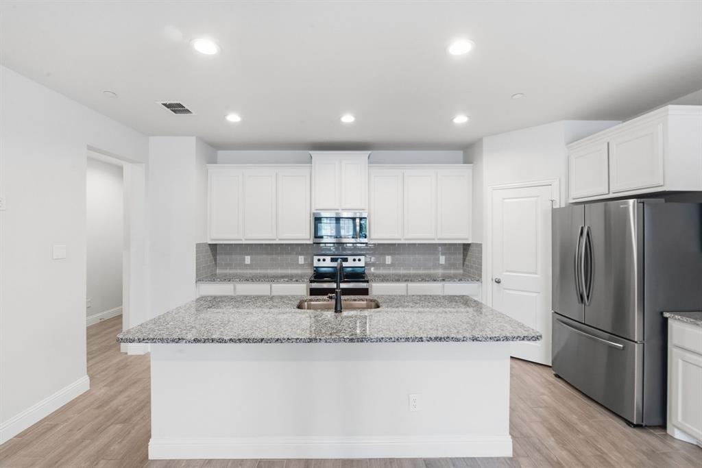 5960 Bursey Road Watauga, TX 76148 - Photo 13 of 38 a kitchen with kitchen island granite countertop a refrigerator a stove a sink cabinets and a counter top space