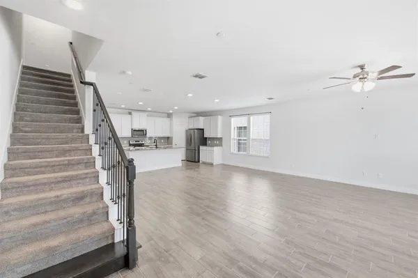 a view of a livingroom with wooden floor and stairs