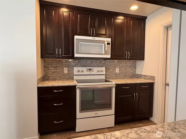 a kitchen with granite countertop stainless steel appliances wooden cabinets and a sink