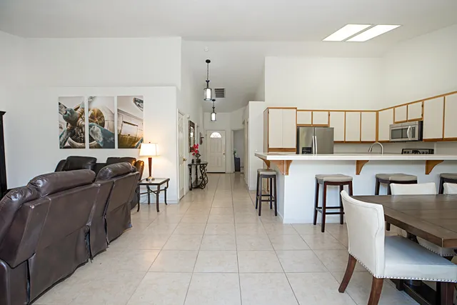a living room with stainless steel appliances furniture a rug and a kitchen view