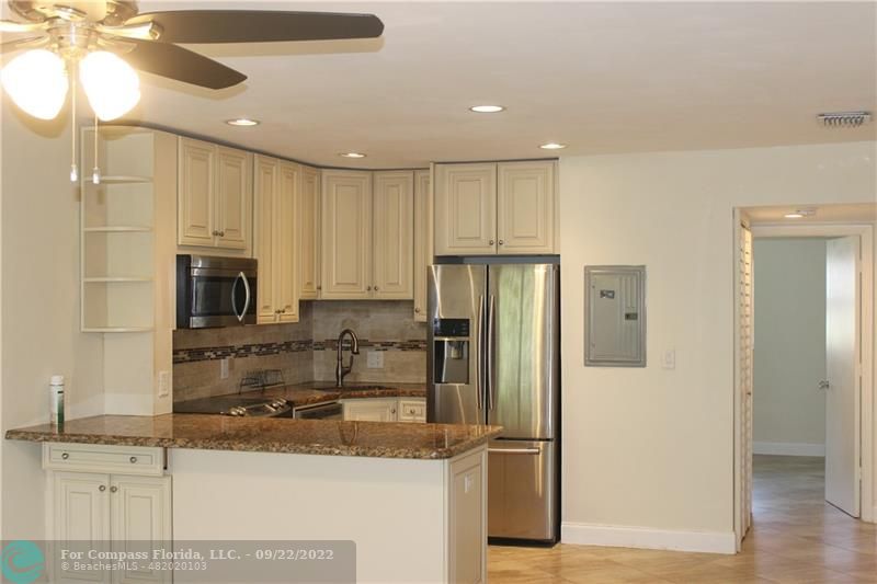 a kitchen with stainless steel appliances granite countertop a refrigerator a oven a sink and white cabinets