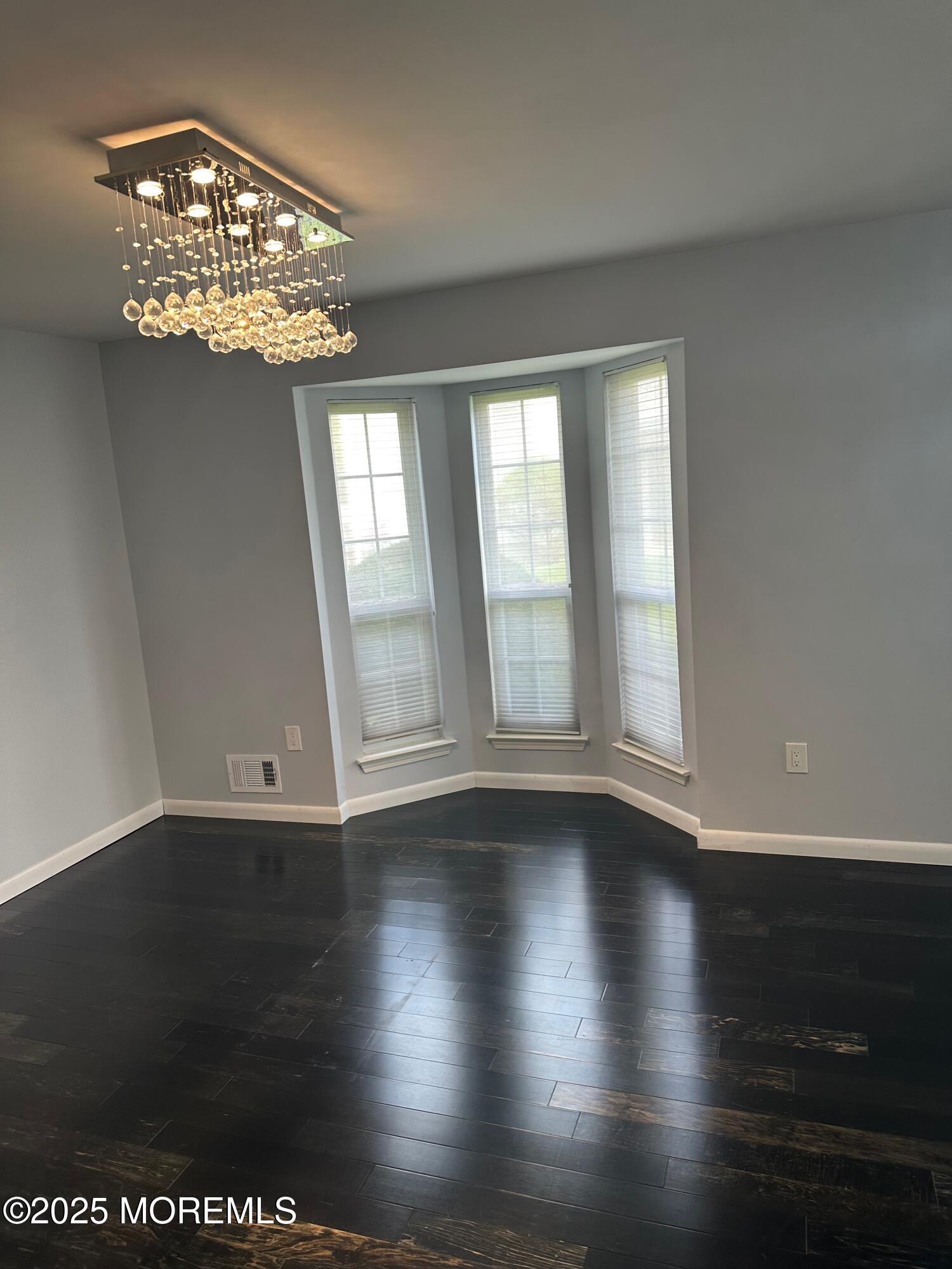36 Alpine Road, Unit 169 Holmdel, NJ 07733 - Photo 9 of 19 an empty room with wooden floor chandelier and windows