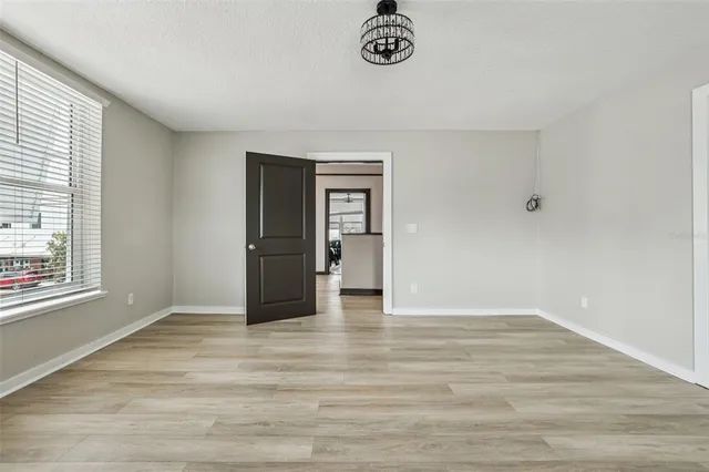 a view of an empty room with window and wooden floor