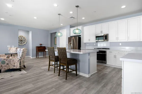 a kitchen with kitchen island granite countertop wooden floors and white cabinets