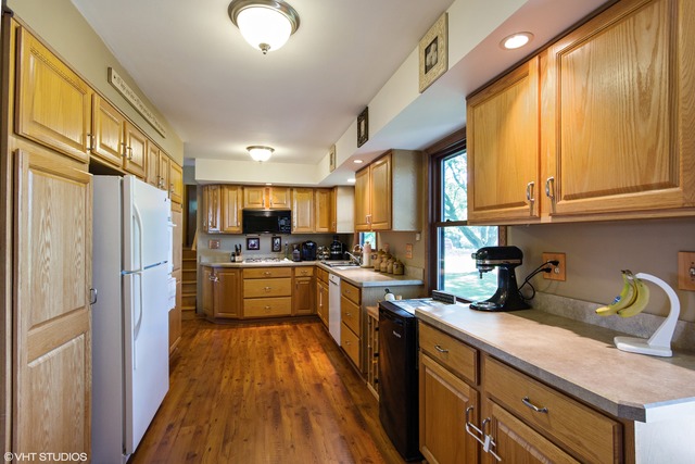 2541 Little Rock Road Plano, IL 60545 - Photo 3 of 13 a kitchen with stainless steel appliances granite countertop a refrigerator a sink dishwasher a stove and white countertops with wooden floor