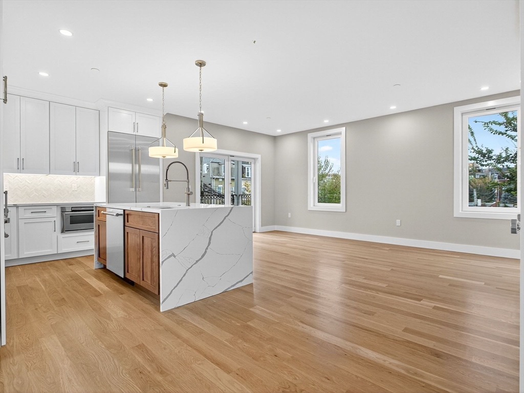 551 East 7th Street, Unit 3 Boston, MA 02127 - Photo 3 of 15 a kitchen with stainless steel appliances granite countertop a stove a sink a refrigerator and white cabinets with wooden floor