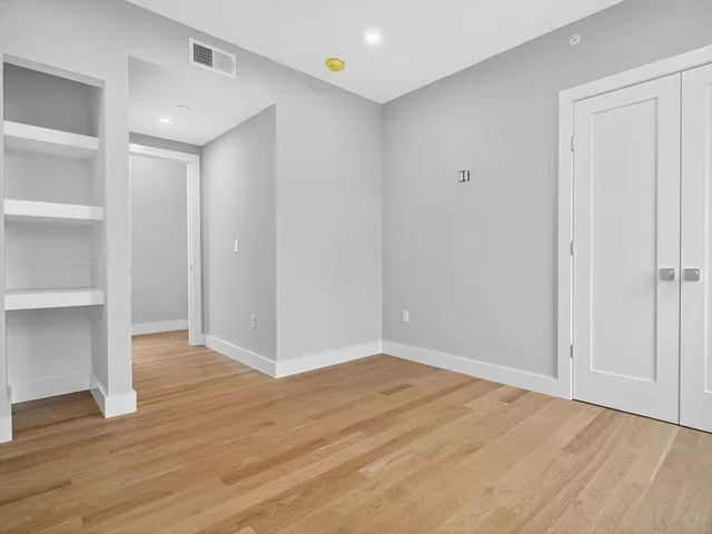 a view of an empty room with wooden floor and closet