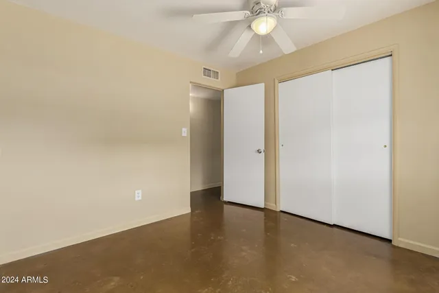 an empty room with a ceiling fan and carpet