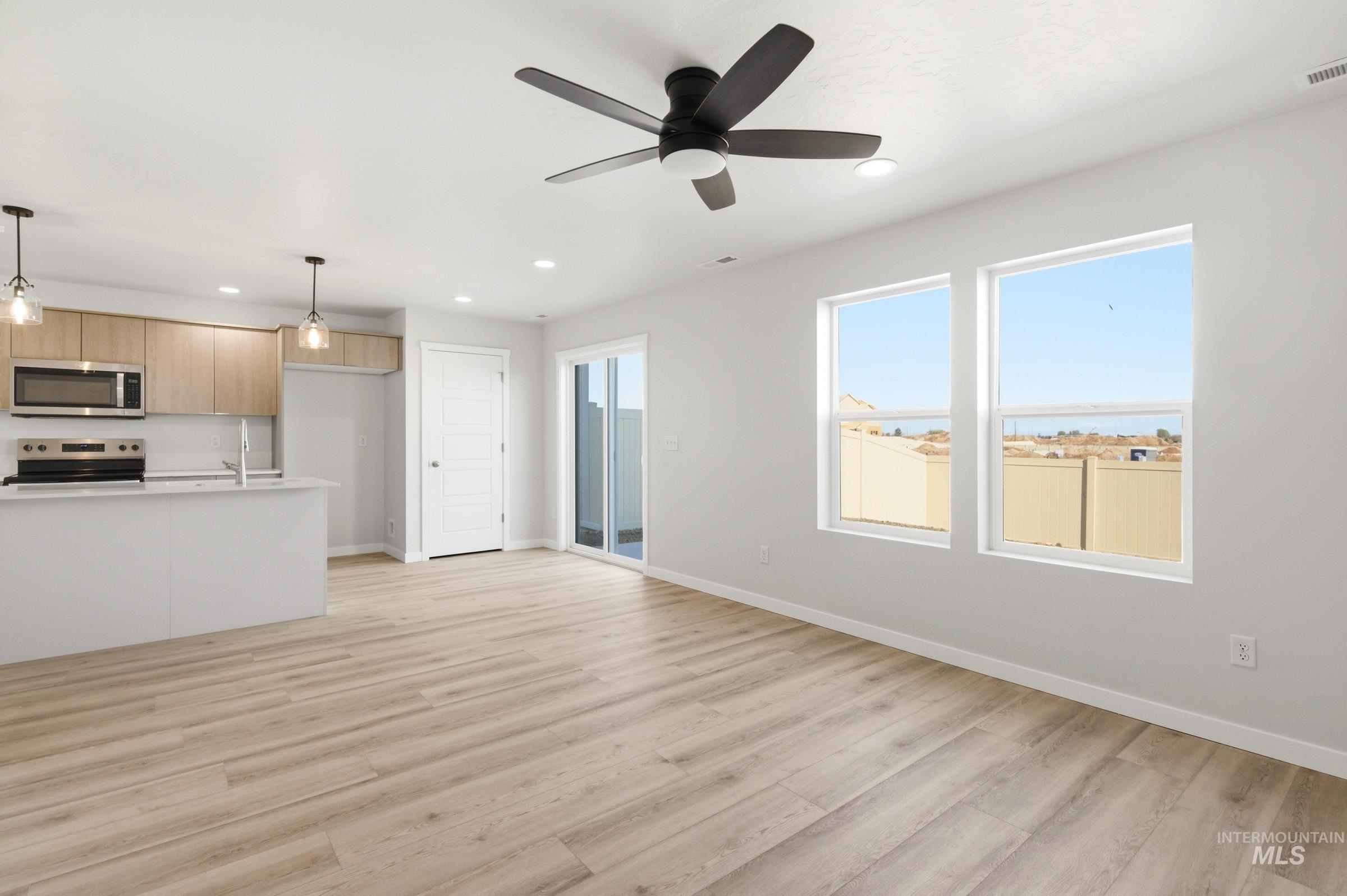10806 Rutland Street Caldwell, ID 83605 - Photo 11 of 21 Open concept living space featuring wood-finish flooring, two large windows, and a sliding glass door