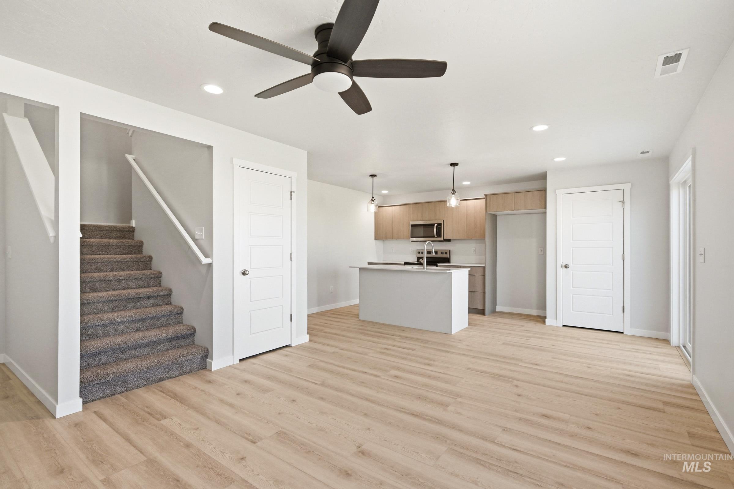 10806 Rutland Street Caldwell, ID 83605 - Photo 12 of 21 Open-concept living area featuring wood-finish flooring, a modern kitchen island with pendant lighting, and light wood cabinetry