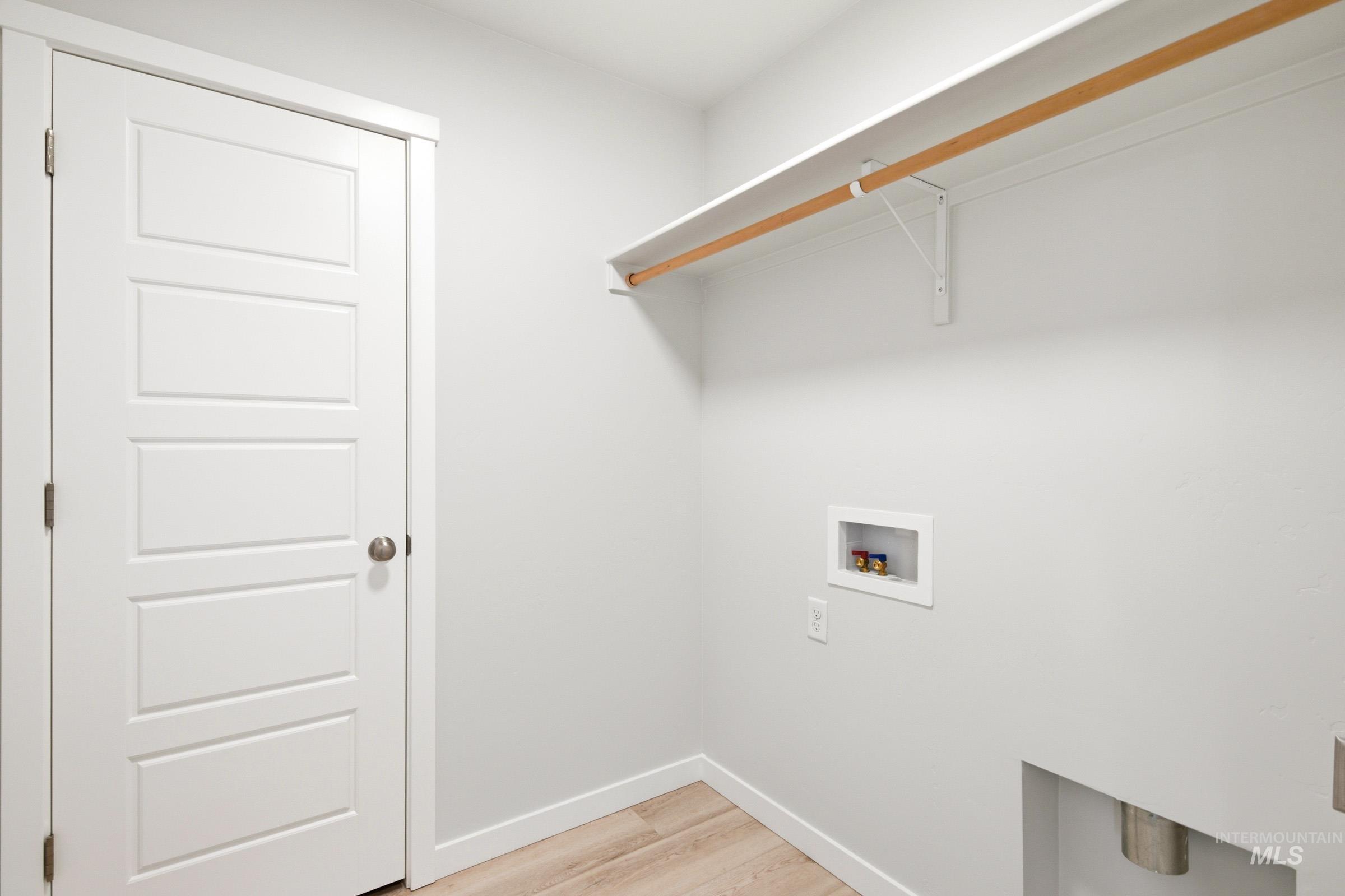 10806 Rutland Street Caldwell, ID 83605 - Photo 17 of 21 Dedicated utility area with wood-finish flooring, light gray walls, white trim, and a white paneled door with brushed nickel hardware