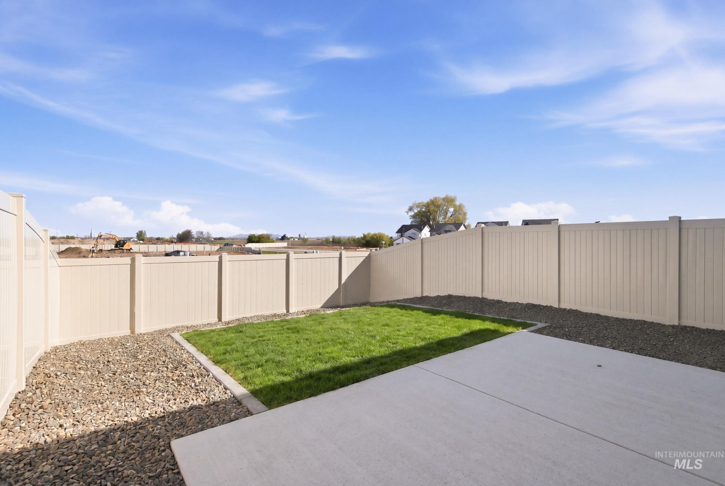 10806 Rutland Street Caldwell, ID 83605 - Photo 21 of 21 Fenced backyard featuring a concrete patio, a central lawn area, and surrounding gravel beds