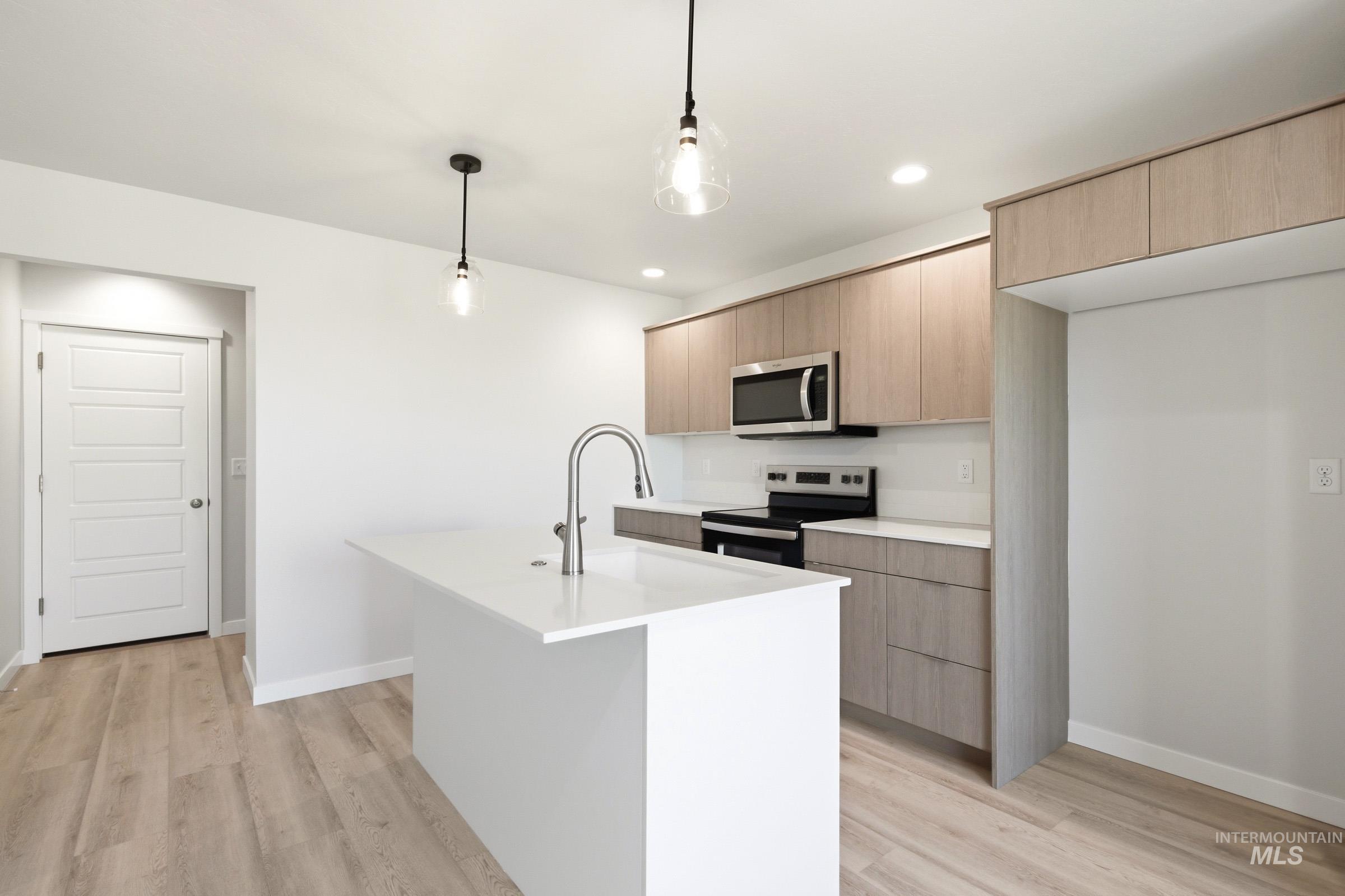 10806 Rutland Street Caldwell, ID 83605 - Photo 3 of 21 Contemporary kitchen featuring wood-finish cabinetry, stainless steel appliances, and an island with a white countertop and gooseneck faucet